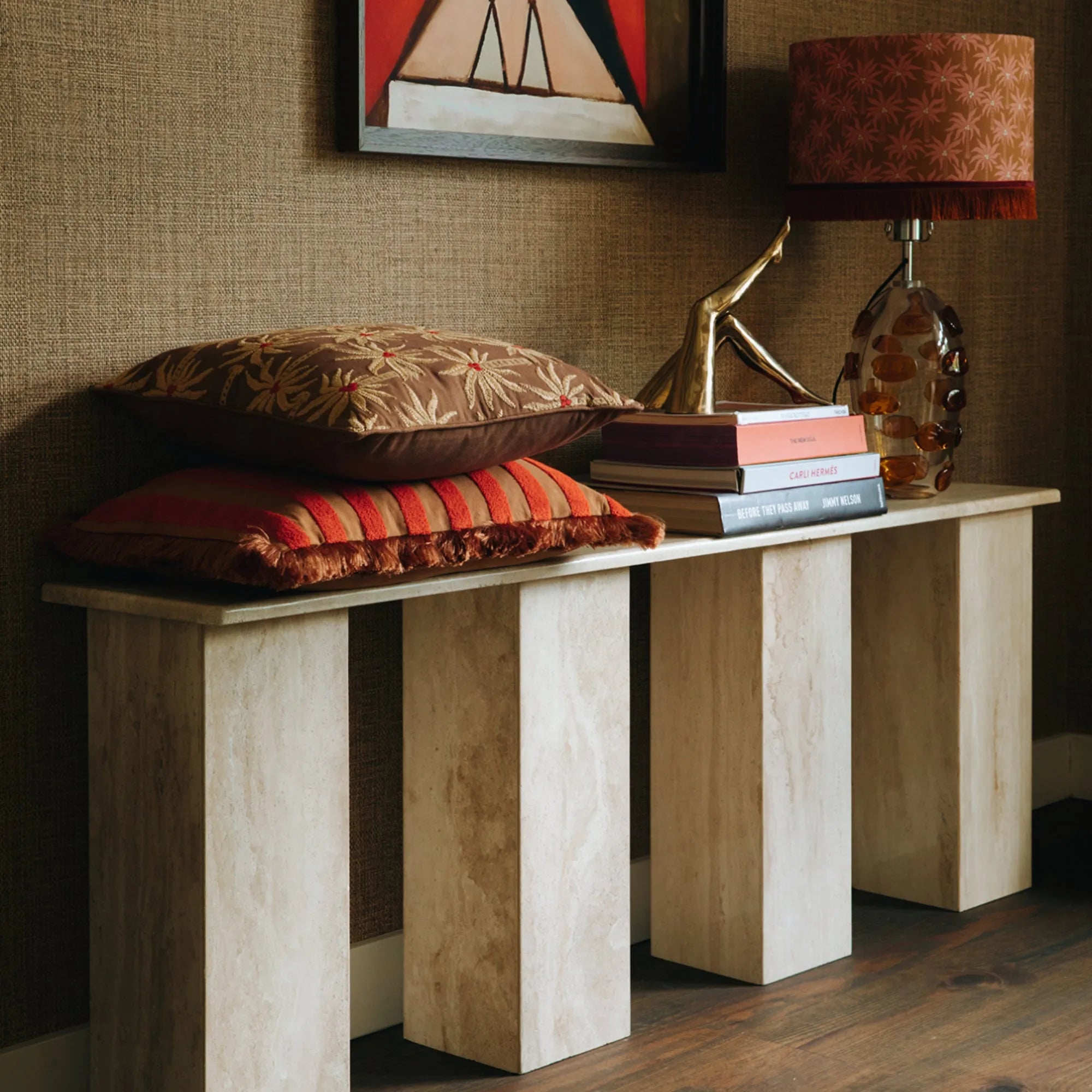 A top view of a Laura Cushion styled on a bed with layered textiles